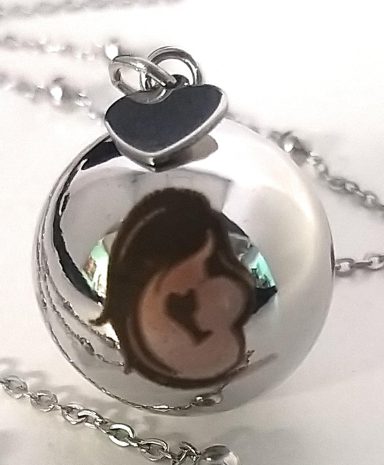 Silver locket with a heart charm and a silhouette of a pregnant woman.